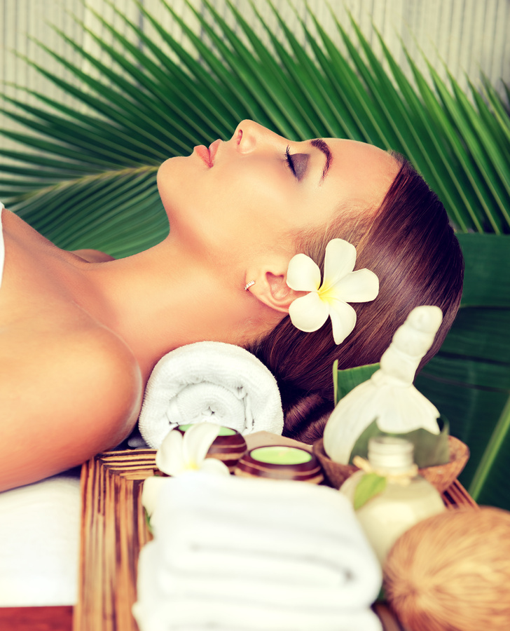 Portrait of young woman lays on massage table.